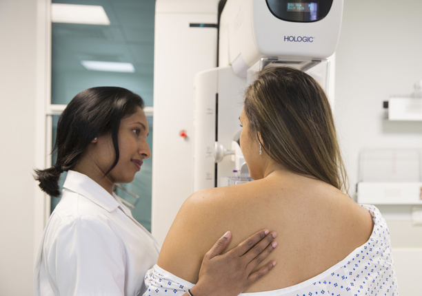 Patient with a diagnostic mammogram in the background and a nurse supporting the patient