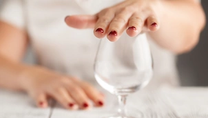 Detail of a lady's hand over an empty wine glass