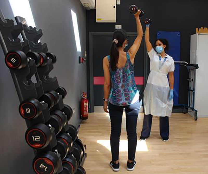 A patient exercises her shoulder in the gym