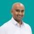 Headshot of consultant Janindra Warusavitarne on a green background