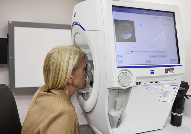 A woman receiving a visual fields eye test (diagnostic machine) at The London Clinic