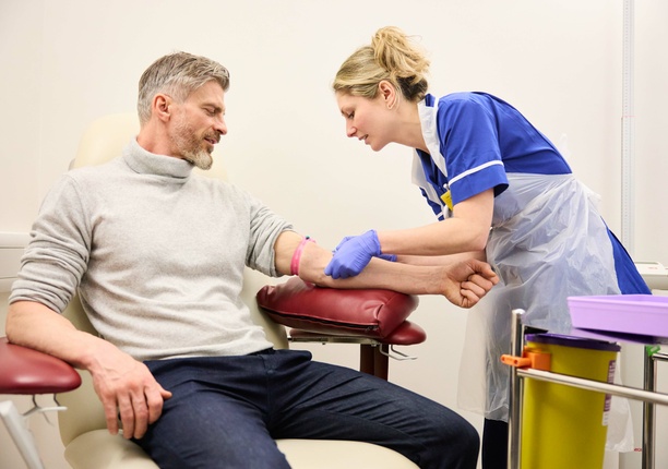 A patient is sat with a nurse checking vitals and skin, ahead of a blood test.