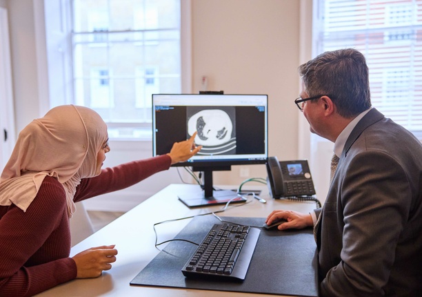 A consultant and patient looking at a scan on the screen, discussing treatment options for lung concerns