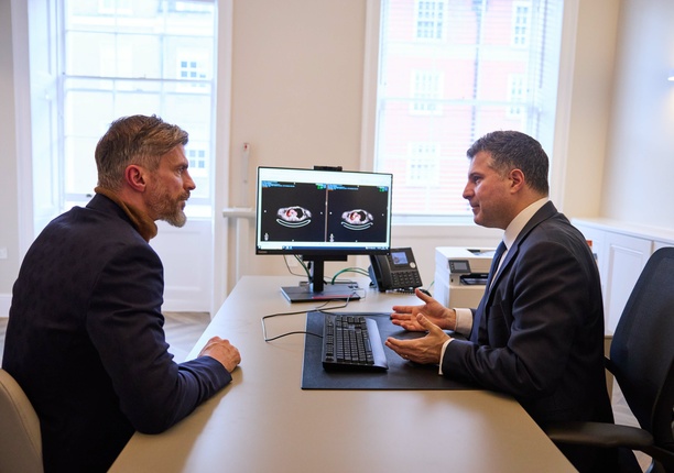 A photo of a patient (model) with a consultant in the foreground, discussing a scan of lungs in the background