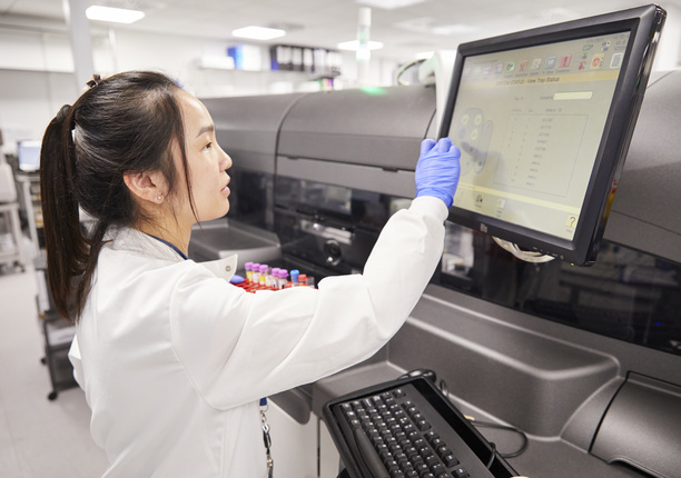A photo of a clinical pathologist inputting data into a screen, holding on to vials in the London Clinic's pathology lab