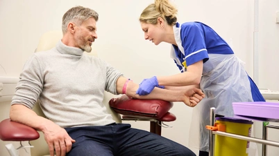 A patient is sat with a nurse checking vitals and skin, ahead of a blood test.