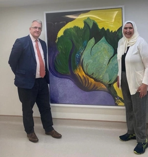 Noura with Dr John Goldstone, Clinical Director for Intensive Care Medicine at The London Clinic, standing by a picture in the Intensive Care Unit (ICU) that Noura painted and donated to the Clinic while she was a patient in the ICU.   