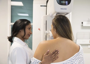 Patient with a diagnostic mammogram in the background and a nurse supporting the patient