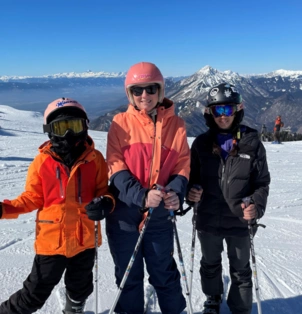 A photo of Andrea, a London Clinic patient, with her two children, all dressed in ski gear on a mountain! Andrea is smiling.