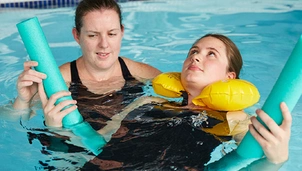 a therapist provides a patient with aquatic therapy in the pool