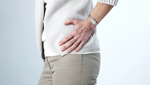 a person holds their hip in pain
