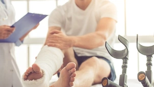 a man sits in a hospital bed with a leg in bandages