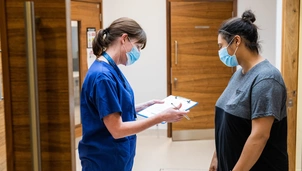 nurse with clipboard talking to patient