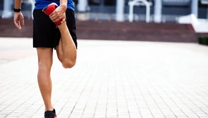 A male runner stretching his leg by bending his knee behind him