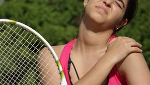 a tennis player grips her shoulder in pain
