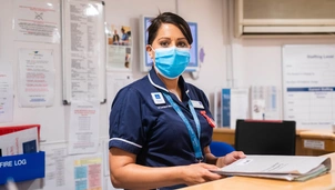A nurse wearing a mask looking at the camera
