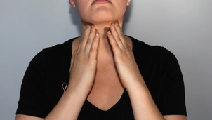 A lady feels her lymph nodes on her neck
