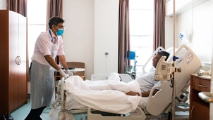 Doctor wearing mask stands by patient bed
