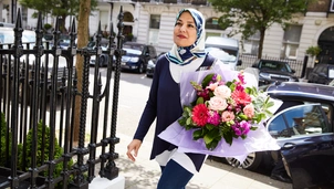 A woman holding flowers walking into the hospital