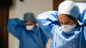 An image of two nurses putting on PPE