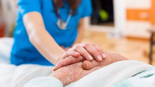 A nurse holding the hands of a patient