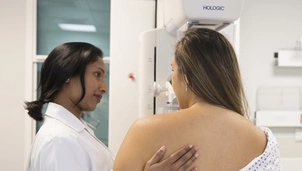 Patient with a diagnostic mammogram in the background and a nurse supporting the patient