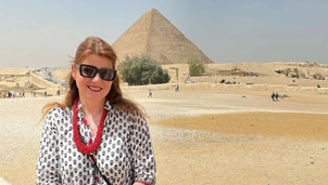 A photo of the London Clinic patient, Andrea, in the foreground with the pyramids of Egypt behind her, smiling and happy.