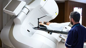 A photo of a radiologist ensuring a patient is safe whilst the linac stereotactic radiotherapy machine is in progress.