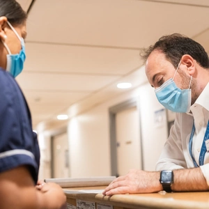 A doctor and nurse talking over a desk