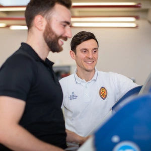 A physiotherapy team member helping a patient on a treadmill