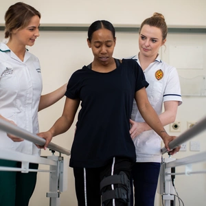 two physios help patient walk