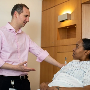 Consultant speaks with patient in bed