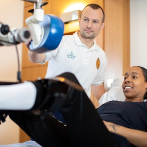Physio watches patient do exercises on bed