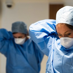An image of two nurses putting on PPE