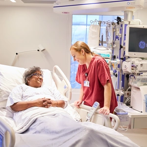 A patient smiling at a member of staff from her bed