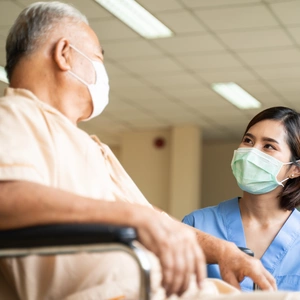 Image of a nurse talking to a patient in a wheelchair