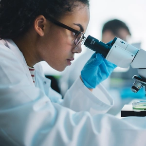 A lady looking through a microscope