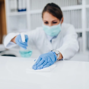 A lady cleaning a desktop with spray