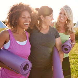 Group Of Mature Female Friends On Outdoor Yoga Retreat Walking Along Path Through Campsite