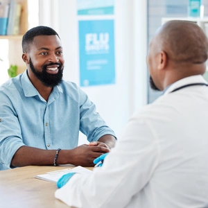 Doctor and healthcare consultation with a wellness and hospital worker in a office. Consulting, patient and happy male with a smile from health communication and expert advice in a clinic