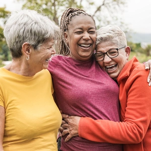 Happy multiracial senior women having fun together outdoor - Elderly generation people hugging each other at park