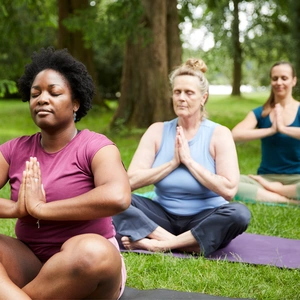Group of diverse women doing yoga exercises together in park in summer and having fun