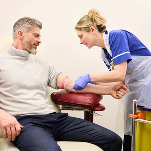 A patient is sat with a nurse checking vitals and skin, ahead of a blood test.