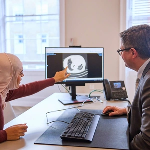 A consultant and patient looking at a scan on the screen, discussing treatment options for lung concerns