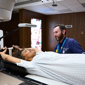 A photo of a radiologist ensuring a patient is safe whilst the linac stereotactic radiotherapy machine is in progress.