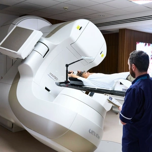 A photo of a radiologist ensuring a patient is safe whilst the linac stereotactic radiotherapy machine is in progress.