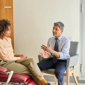 A London Clinic Lung Centre consultant discussing treatment options with a patient, sat in a chair looking out at the window happy!