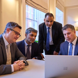 A photo of all the Lung Centre consultants, sitting in a group gathered around a laptop looking and discussing results.