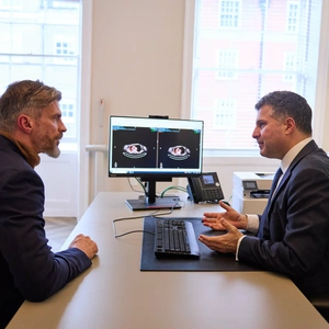 A photo of a patient (model) with a consultant in the foreground, discussing a scan of lungs in the background