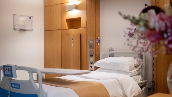 An image of the Superior Room at The London Clinic, with a focus on the patient bed but with flowers in the foreground 